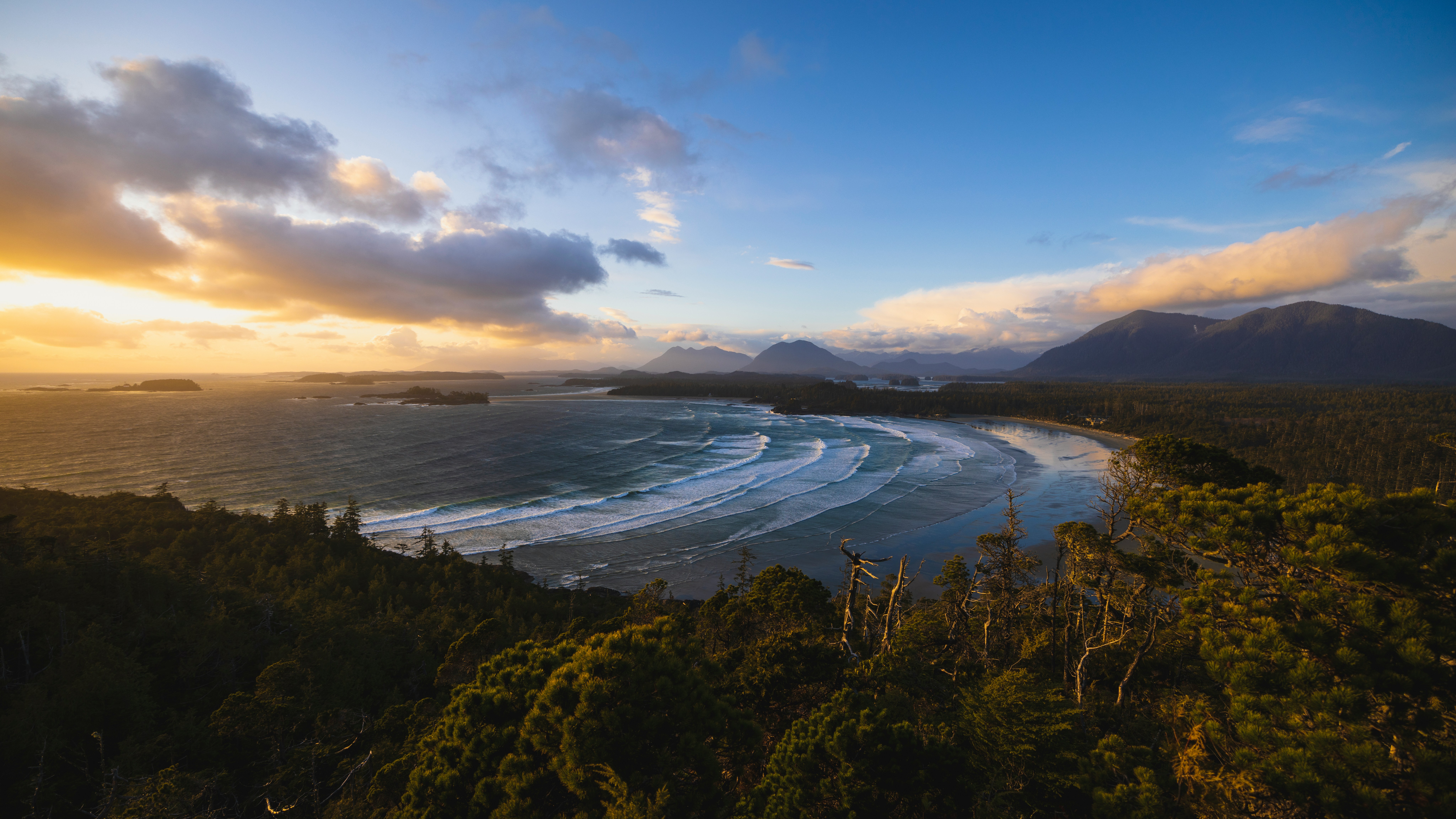 Waves curling into a wide beach on the wild Pacific coast near Tofino, Vancouver Island, at sunset