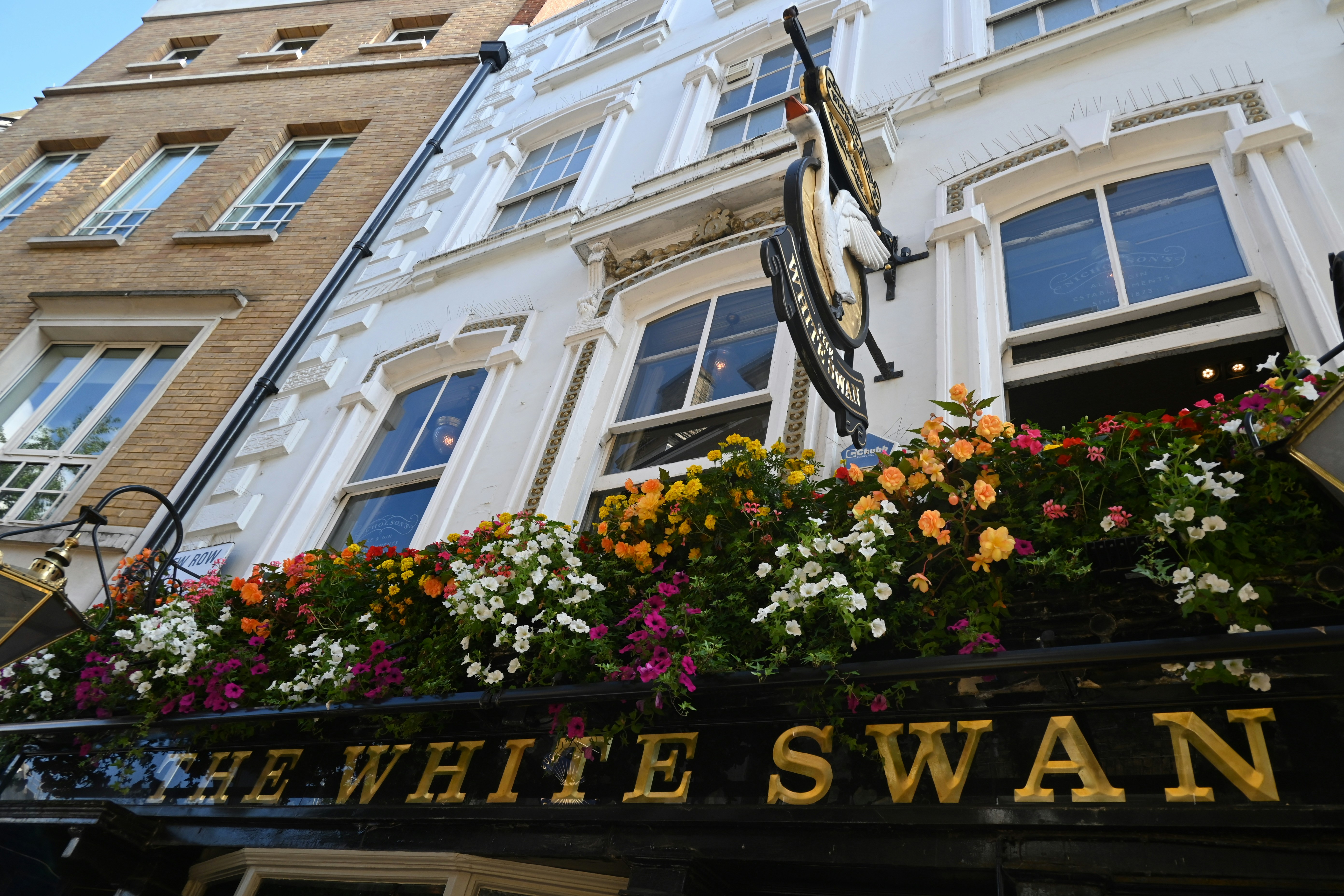 A traditional English pub exterior with hanging flower baskets and warm interior lighting