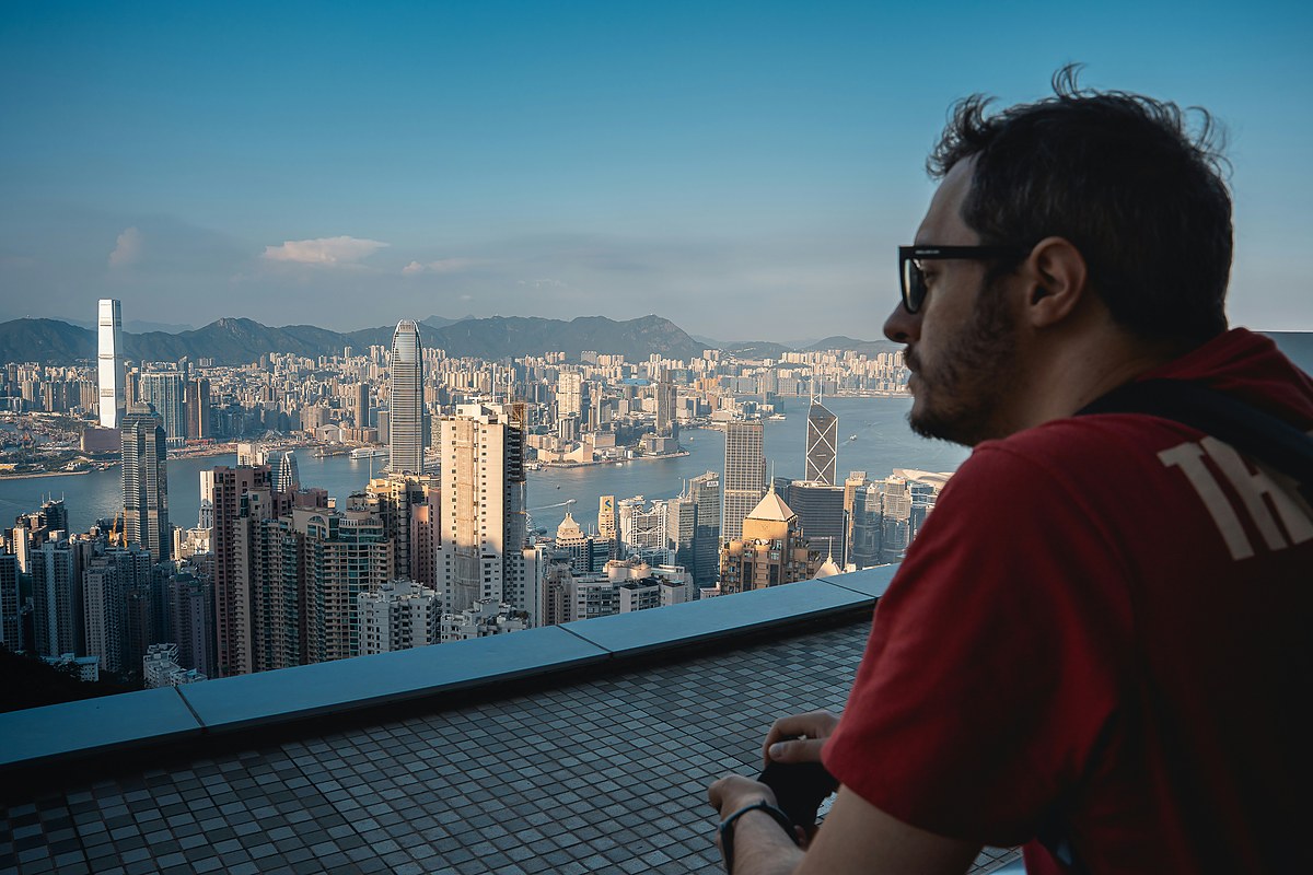 A traveler looks out over an unfamiliar city skyline at dusk