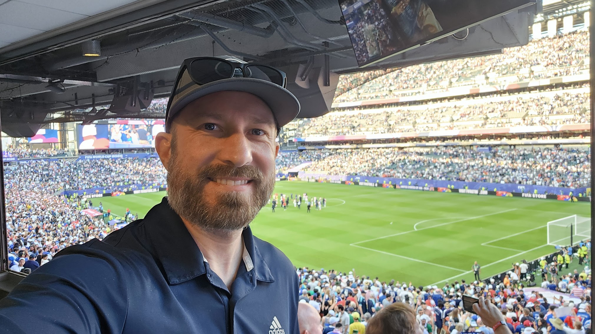 Brian Schwan smiling for a selfie with the packed stadium and pitch at Lincoln Financial Field behind him