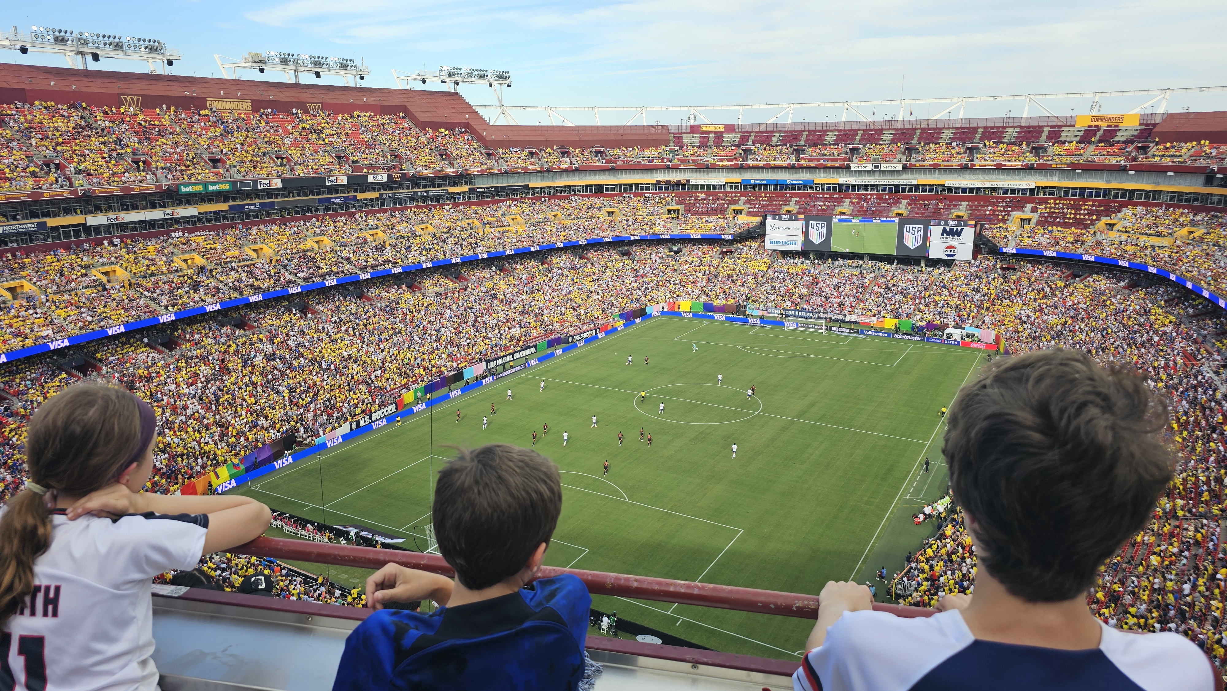 Kids in US jerseys watching the national team play, eyes fixed on the field