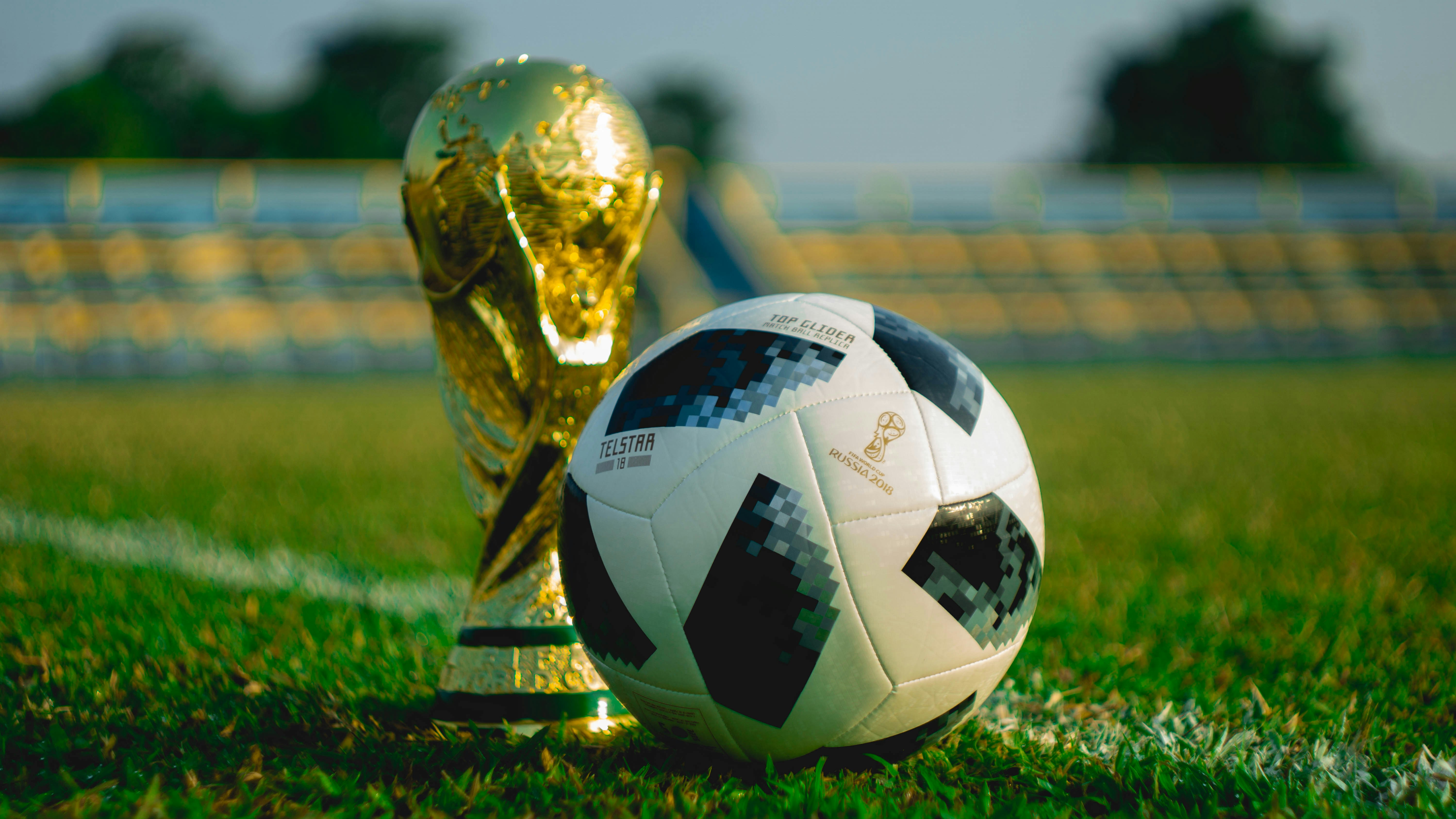The FIFA World Cup trophy gleaming under stadium lights, golden against a dark background