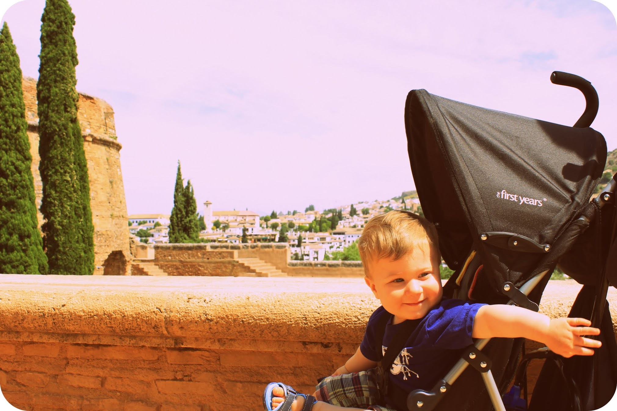 A young child in a stroller at the Alhambra complex in Granada, Spain, with the city visible in the hills behind