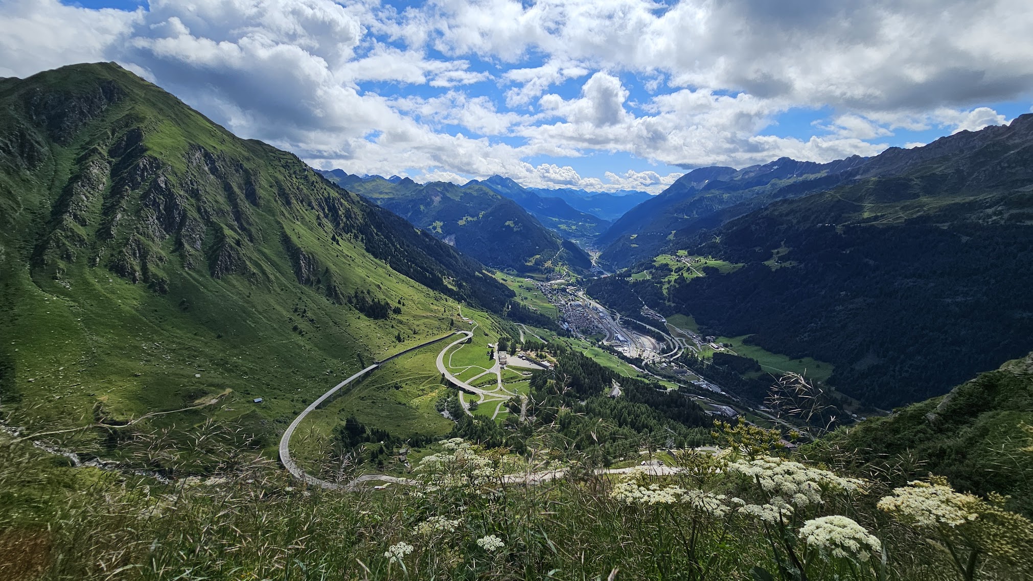 A hiking trail through an alpine mountain pass in Switzerland, with green meadows and dramatic peaks