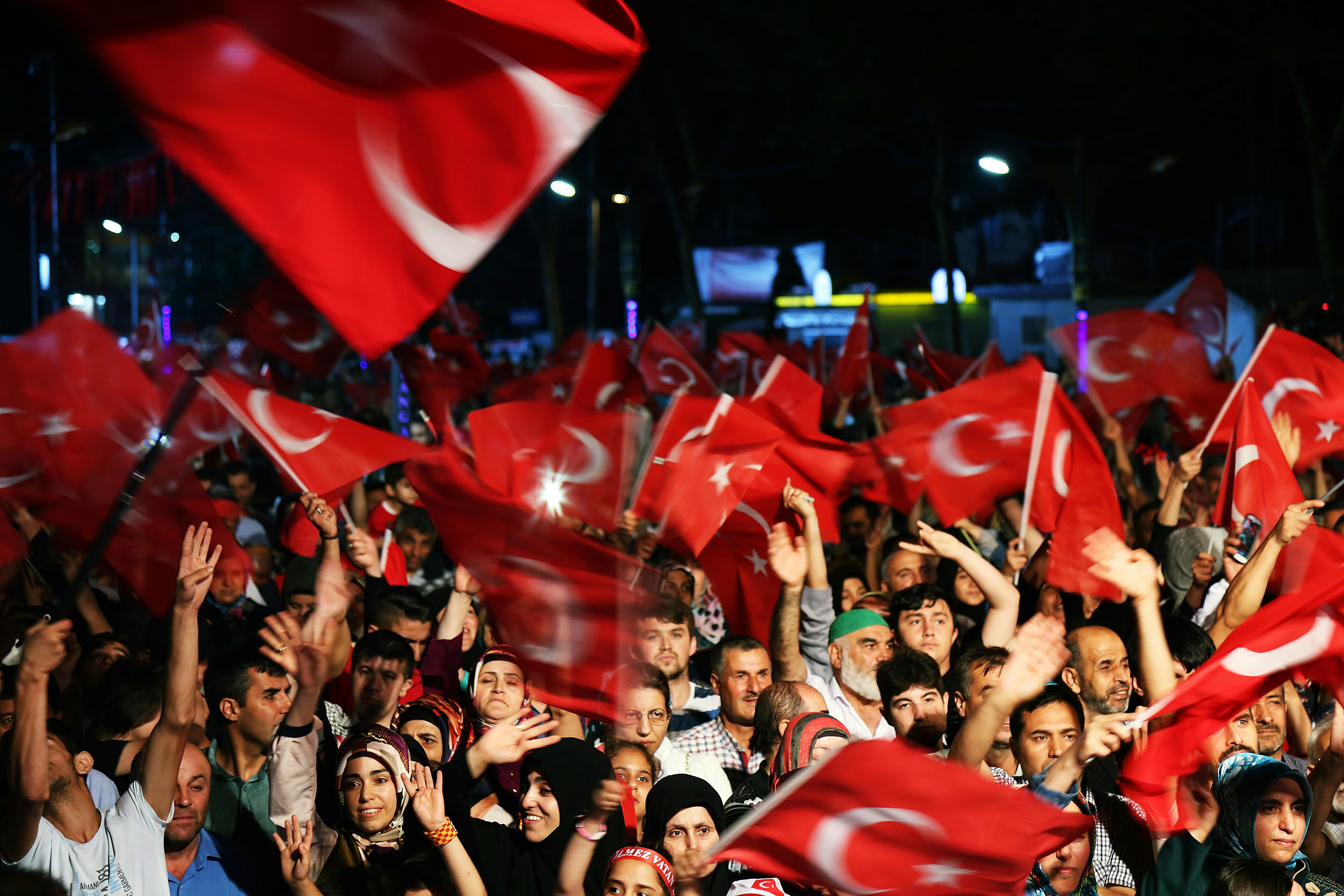 Turkish soccer fans in red and white, cheering in the stands during a national team match