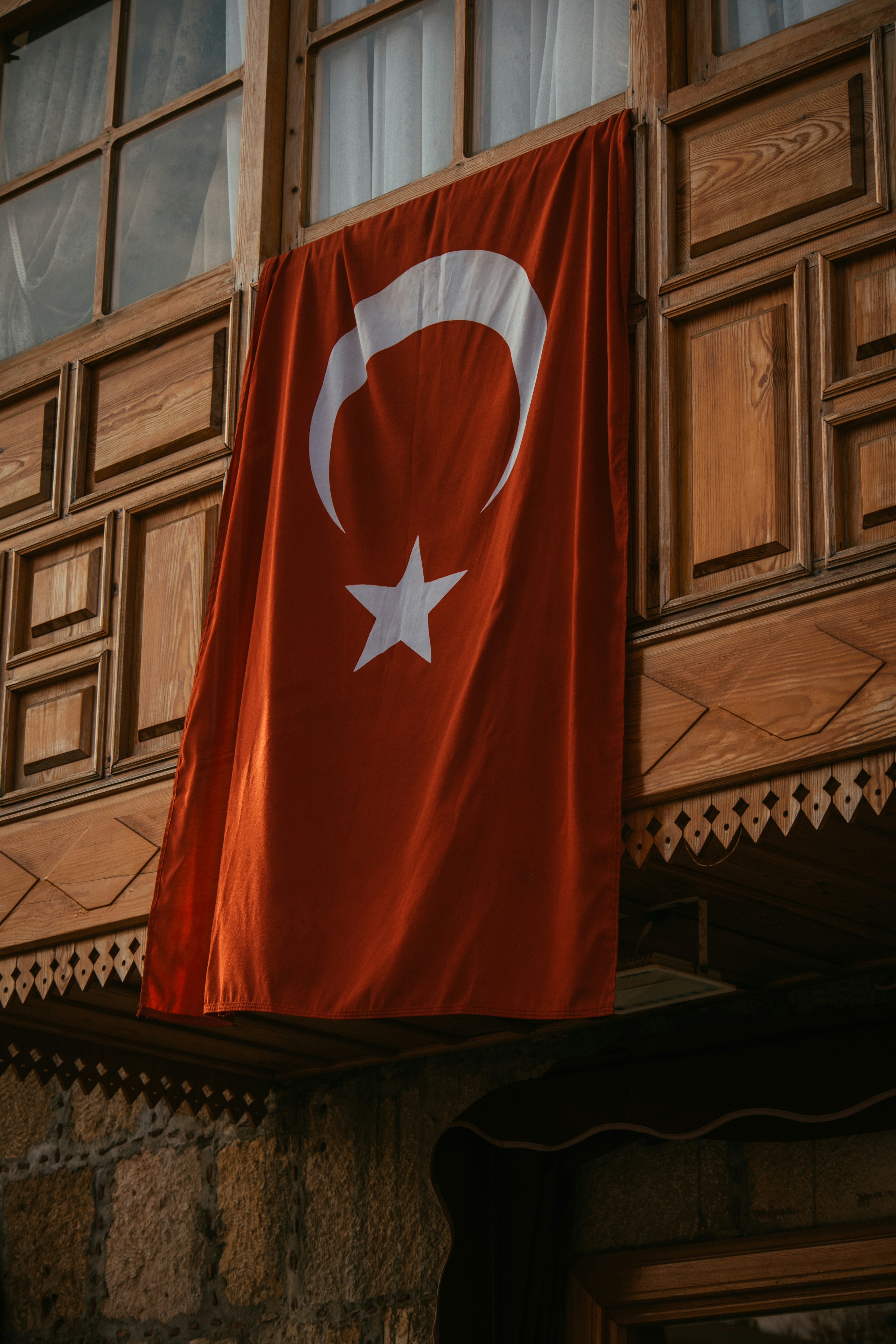 The Turkish flag, a red field with a white crescent and star, flying against a blue sky
